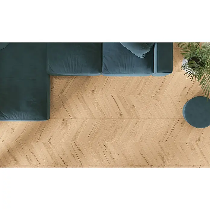 Feinsteinzeug in antiker honig Holzoptik 20x120 - Italienische Fliesen -  - Heller Chevron-Holzboden in einem Wohnzimmer, mit dunkelgrünem Ecksofa, rundem Beistelltisch und Topfpflanze.
