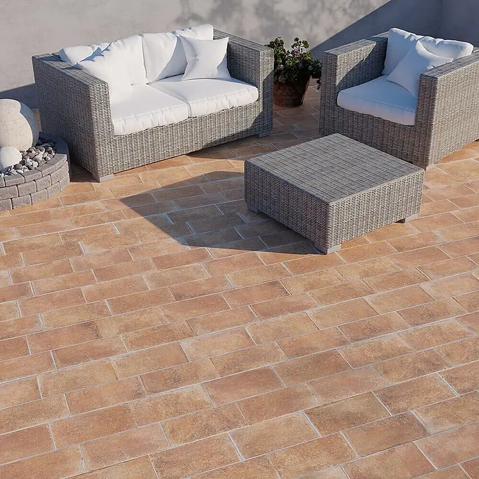 Feinsteinzeug in Terrakottaoptik 15x30, 20 mm, rutschhemmend -  - Gartensitzgruppe aus grauem Polyrattan mit weißen Kissen (Sofa, Sessel, Tisch) auf Terrakotta-Fliesen.