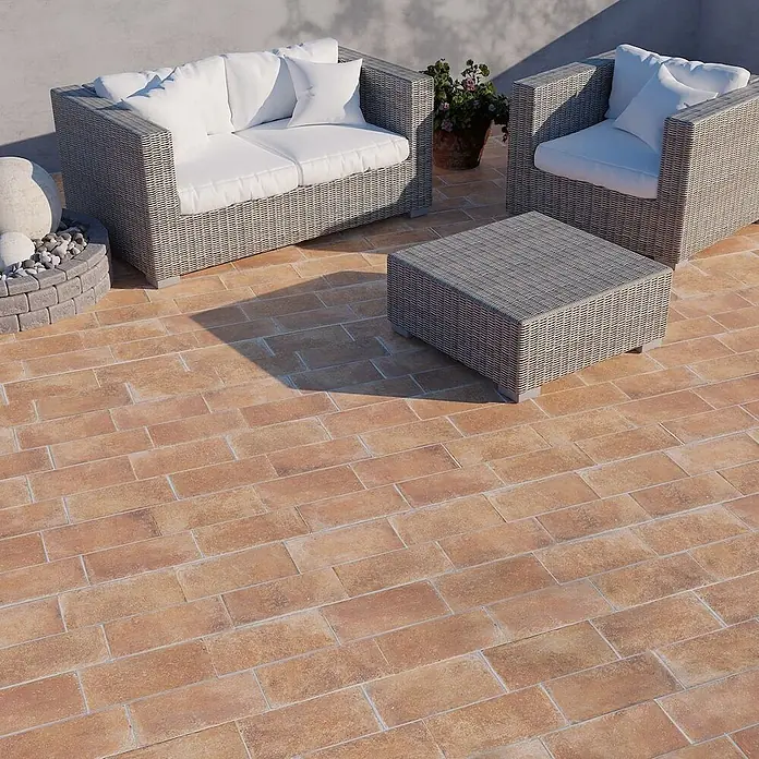 Feinsteinzeug in Terrakottaoptik 15x30, 20 mm, rutschhemmend -  - Graues Korbgeflecht Outdoor-Sofa, Sessel und Couchtisch mit weißen Kissen auf rustikaler Ziegelterrasse.