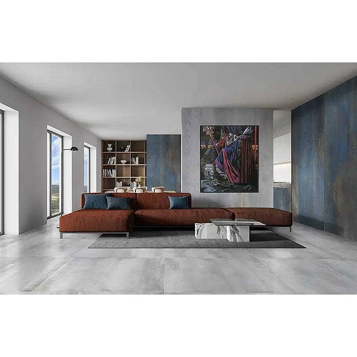 Feinsteinzeug in oxidierter grauer Metalloptik 60x60 - Italienische Fliesen -  - Ein modernes Wohnzimmer mit rostfarbener L-förmiger Couch, Marmor-Couchtisch und großem Kunstwerk an strukturierten blau-grauen Wänden.
