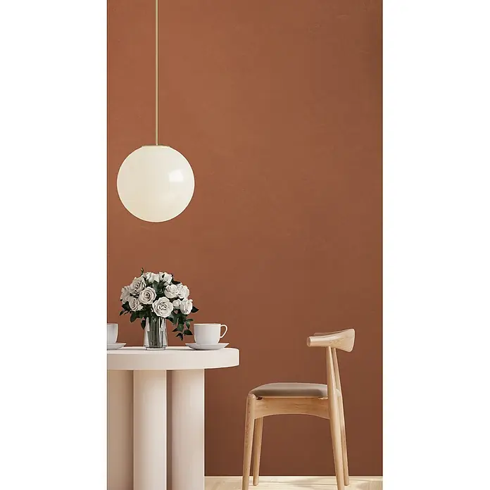 Feinsteinzeug in farbiger roter Betonoptik 60x120 - Italienische Fliesen -  - Minimalistischer Essbereich mit rundem weißen Tisch, Holzstuhl, Pendelleuchte und weißen Rosen.