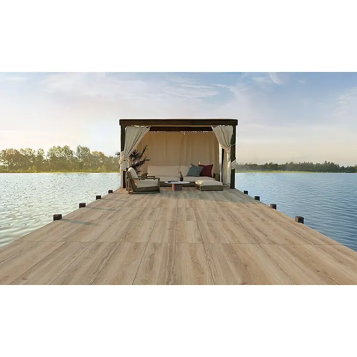 Feinsteinzeug in honigfarbener Holzoptik 20x120, rutschhemmend -  - Helle Holzoptikfliesen bilden eine Außenterrasse mit Lounge-Bereich über einem See.