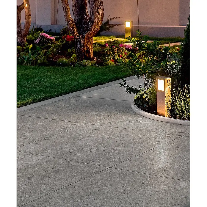 Feinsteinzeug in grauer Steinoptik 60x120, 20 mm, rutschhemmend -  - Graue, gesprenkelte Outdoor-Pflasterfliesen bilden einen Gartenweg, beleuchtet von modernen Landschaftsleuchten.