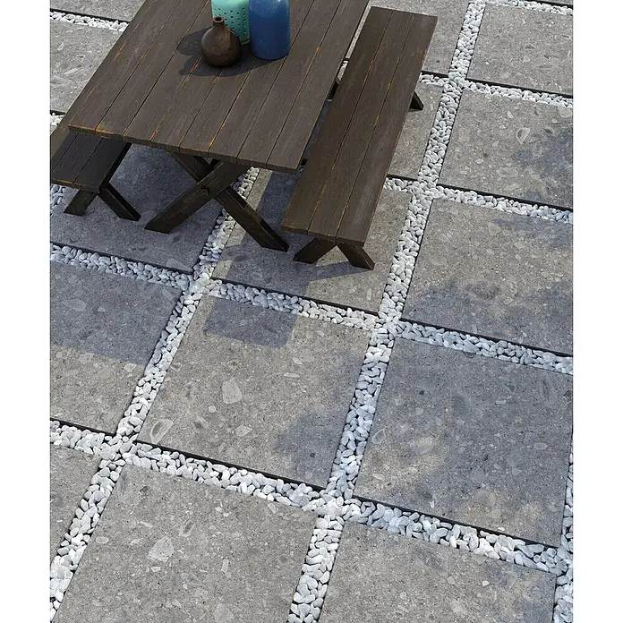 Feinsteinzeug in grauer Steinoptik 60x120, 20 mm, rutschhemmend -  - Graue quadratische Terrassenplatten mit weißen Kieselsteinen und dunkler Holz-Picknickgarnitur.