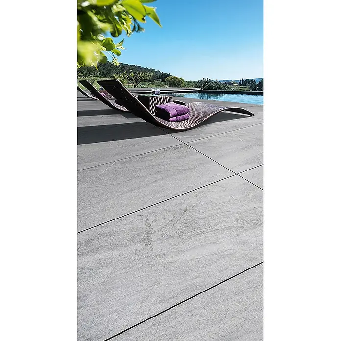 Feinsteinzeug in grauer Steinoptik 60x120, 20 mm, rutschhemmend -  - Großformatige graue Outdoor-Fliesen auf einer Terrasse neben einem Swimmingpool mit Liegestühlen.
