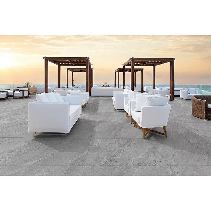 Feinsteinzeug in grauer Steinoptik 60x120, 20 mm, rutschhemmend -  - Große graue Steinoptik-Terrassenfliesen auf einer weitläufigen Lounge-Fläche mit Meerblick.