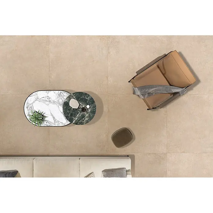 Feinsteinzeug in beiger Betonoptik 120x120 - Italienische Fliesen -  - Helle, großformatige, beigefarbene Bodenfliesen in einem modernen Wohnzimmer mit cremefarbenem Sofa, braunem Sessel und Marmortischen.