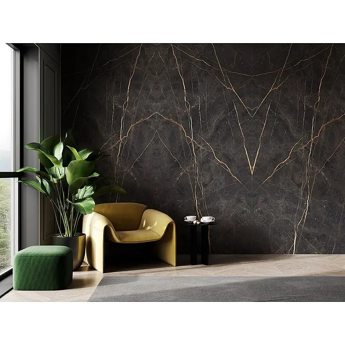 Feinsteinzeug in matter Marmoroptik 120x120 - Italienische Fliesen -  - Luxuriöse dunkle Marmorwand mit goldenen Äderungen in einem modernen Wohnzimmer mit gelbem Sessel und grünem Hocker.