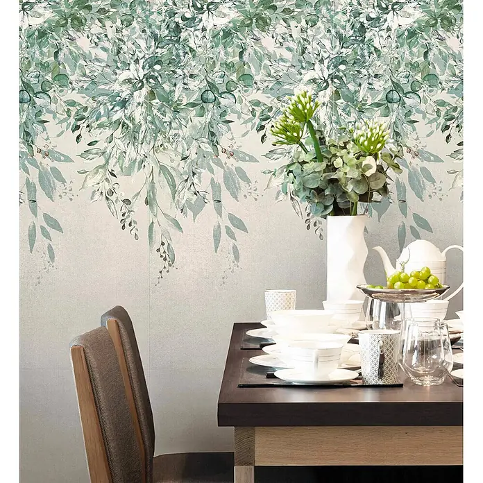 Dekorierte Wandfliese aus Feinsteinzeug 02 60x120 - Italienische Fliesen -  - Tapete mit grün-weißem botanischem Blattmuster, schmückt eine Esszimmerwand über einem gedeckten Tisch.
