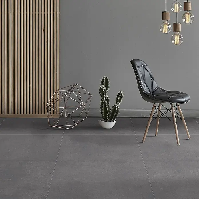 Feinsteinzeug Wandfliese matter schwarzer Harzoptik 20x50 - Ital. Fliesen -  - Ein modernes Interieur mit schwarzem Polsterstuhl, geometrischer Deko, Topfkaktus und Hängelampen vor einer Holzlamellenwand.