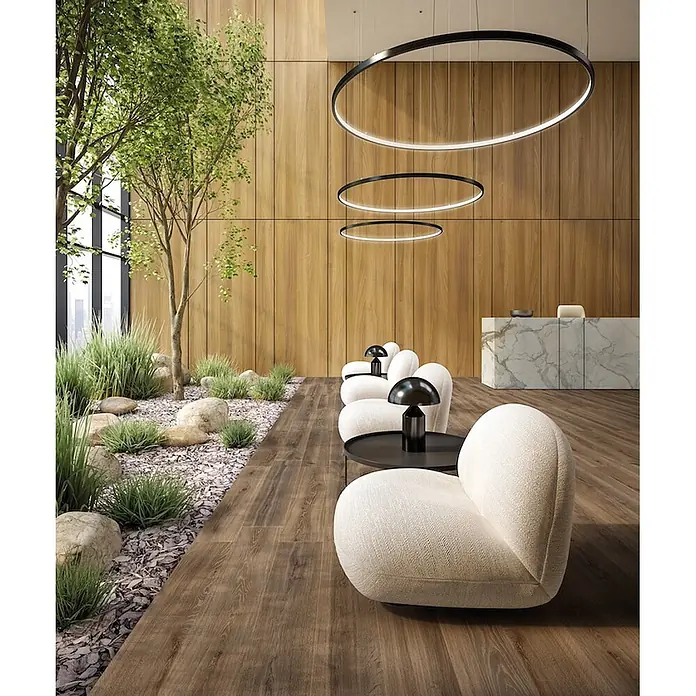 Feinsteinzeug in taupefarbener Holzoptik 20x120 - Italienische Fliesen -  - Moderne cremefarbene Stoff-Sessel, schwarze Beistelltische und Pilzlampen in einer zeitgenössischen Lobby mit Holz und Pflanzen.