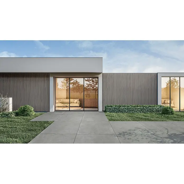 Feinsteinzeug in dunkelgrauer Harzoptik 60x120, rutschhemmend -  - Graue Beton-Terrassenplatten bilden einen modernen Weg vor einem Gebäude mit großen Fenstern und Garten.
