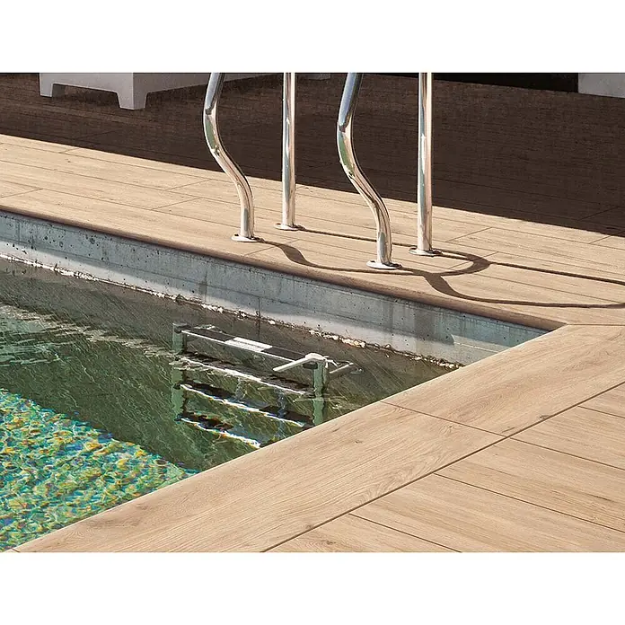 Feinsteinzeug in roher beiger Holzoptik 30x120, rutschhemmend -  - Helle Holzoptik-Fliesen um einen Pool mit Edelstahl-Handläufen und Leiter.