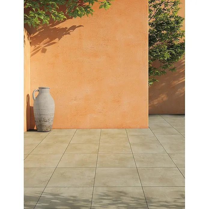 Feinsteinzeug in elfenbein Harzoptik 60x120 - Italienische Fliesen -  - Eine Außenszene mit oranger, strukturierter Wand, rustikaler Vase und hellbeigem Fliesenboden unter Sonnenlicht mit Blattschatten.