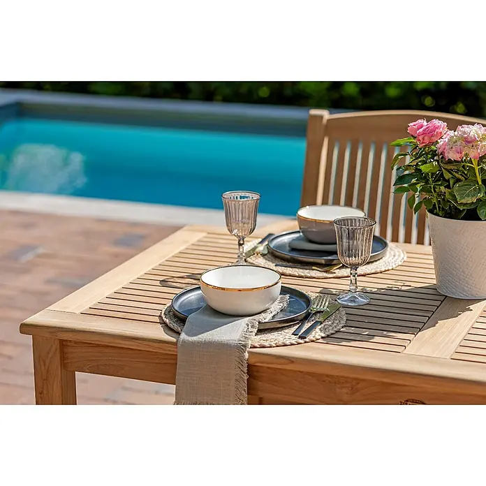 Teak Gartentisch 150 x 80 cm Holztisch wetterfest perfekt verarbeitet -  - Holz-Esstisch für draußen, gedeckt mit Geschirr und Topfpflanze, am Swimmingpool.