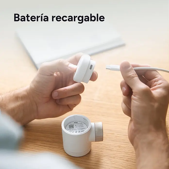 Tado Juego de termostato - Blanco/Negro, Termostáto + Bridge + 2 Cabezales - Manos conectan un cable USB-C blanco a un dispositivo modular blanco, mostrando su batería recargable.