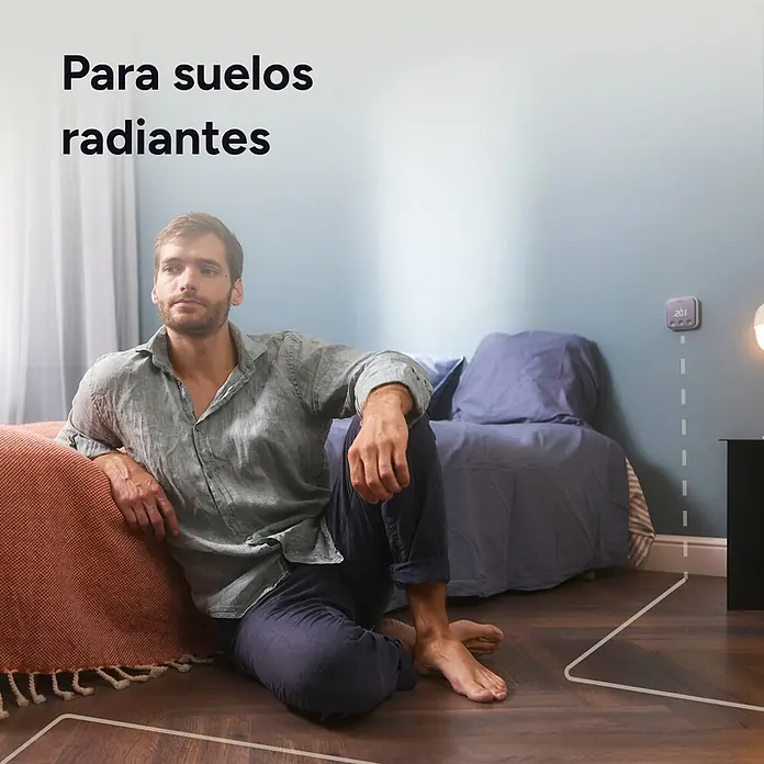 Tado Juego de termostato + Bridge X - Blanco/Negro, Termostáto + Bridge - Termostato inteligente para suelo radiante, muestra 20,1 °C, un hombre sentado cómodamente en el suelo cálido.