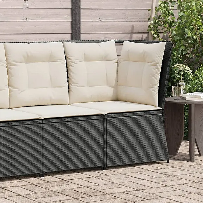 Furnicato Gartensessel aus PE-Rattan, Schwarz -  - Ein L-förmiges, dunkelgraues Rattan-Loungesofa mit dicken cremefarbenen Kissen steht auf einer gepflasterten Terrasse.