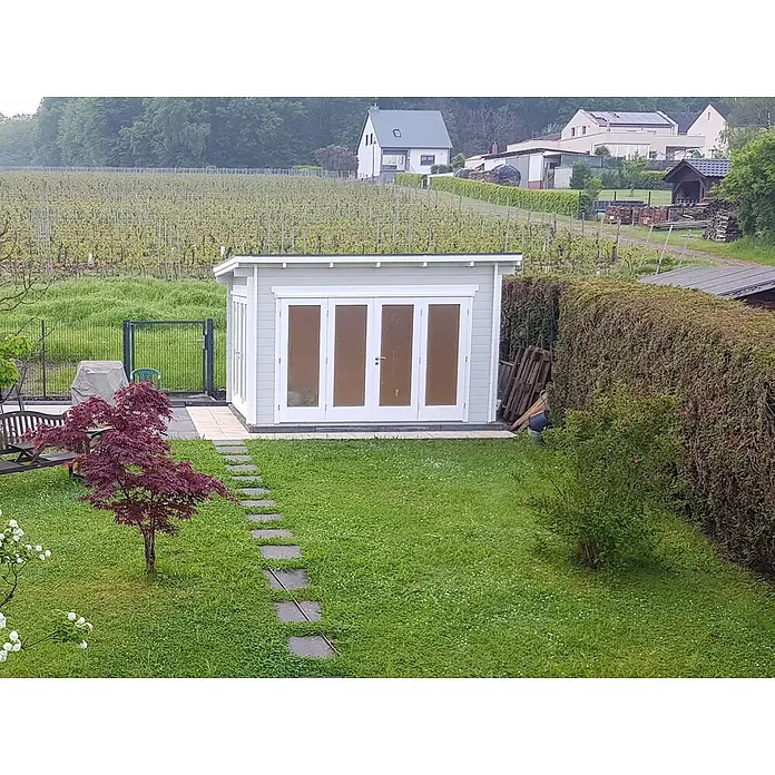 Fjordholz Gartenlounge Modell Sandra 44 A, 13.78  m², Isolierverglasung -  - Ein hellgraues Gartenhaus mit weißen Flügeltüren steht auf einer gepflasterten Fläche in einem grünen Garten.