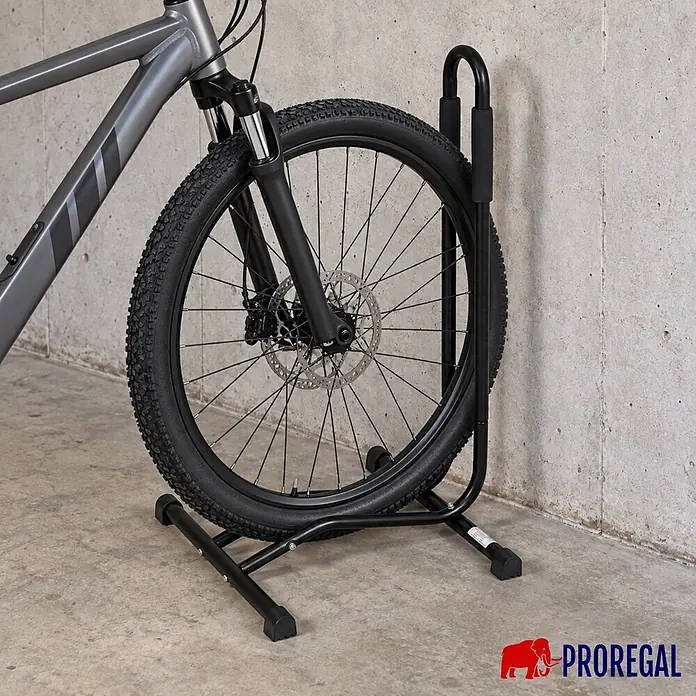 PROREGAL Fahrradständer STAND HxBxT 74x43x43cm -  - Schwarzer Fahrradständer aus Metall hält das Vorderrad eines grauen Fahrrads vor einer Betonwand.