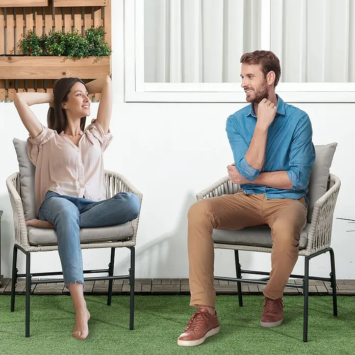 Furnicato Loungesessel-Set 2-teilig, Boho-Look, Beige -  - Zwei hellgraue geflochtene Outdoor-Stühle mit grauen Kissen, von einem Mann und einer Frau auf einer Terrasse genutzt.