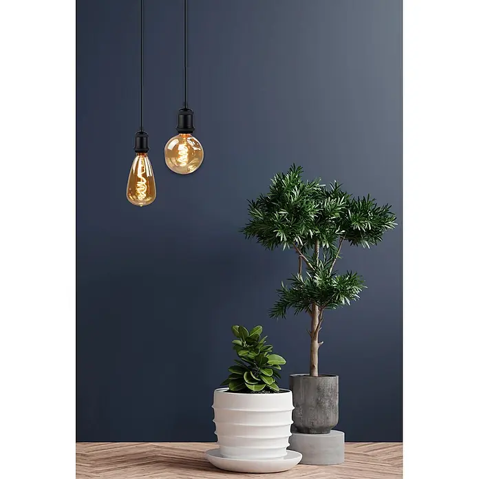ENOVALITE LED-Leuchtmittel E27 4 W 2200 K Warmweiß Dimmbar -  - Zwei Pendelleuchten mit dekorativen bernsteinfarbenen Glühfäden und schwarzen Fassungen vor einer dunkelblauen Wand.