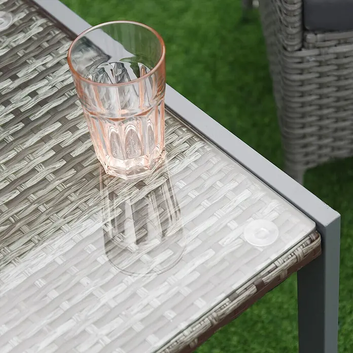 Furnicato Beistelltisch Polyrattan Grau Hartglas 50x49,5x50 cm -  - Ein pfirsichfarbenes Glas steht auf einem grauen Rattan-Outdoor-Tisch mit Glasplatte.