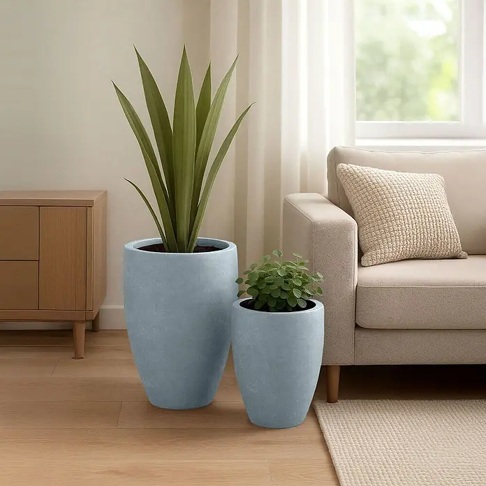 Furnicato Pflanzkübel-Set Fiberclay, 2-teilig, Steinoptik -  - Zwei hellgrau-blaue Pflanzgefäße unterschiedlicher Größe mit Pflanzen in einem modernen Wohnzimmer.