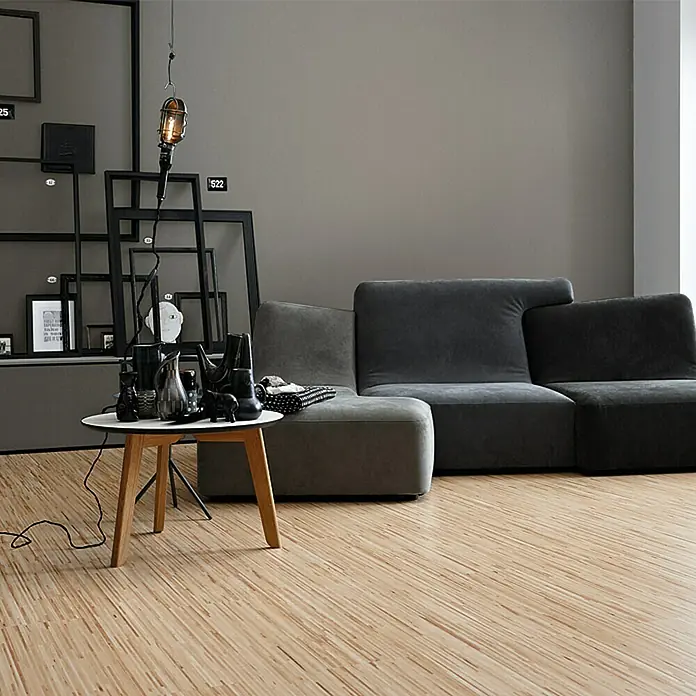 SCHÖNER WOHNEN-Farbe Wandfarbe Trendfarbe - Manhattan, Matt, 1 l, Konservierungsmittelfrei - Einrichtung mit grauer Couch, Beistelltisch mit Dekoration und einer Hängelampe vor einer grauen Wand, die ein modernes Ambiente schafft.