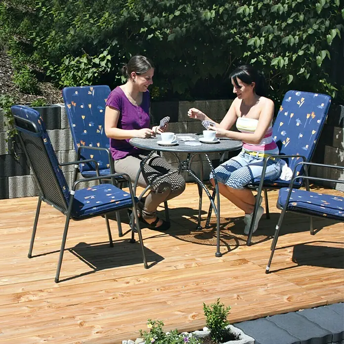 Christoph Streifen-Fundament - 50 x 15 x 7,2 cm, Beton - Zwei Frauen sitzen an einem Gartentisch auf einer Terrasse und spielen Karten. Die blauen Stühle mit Auflagen passen gut zur Umgebung.