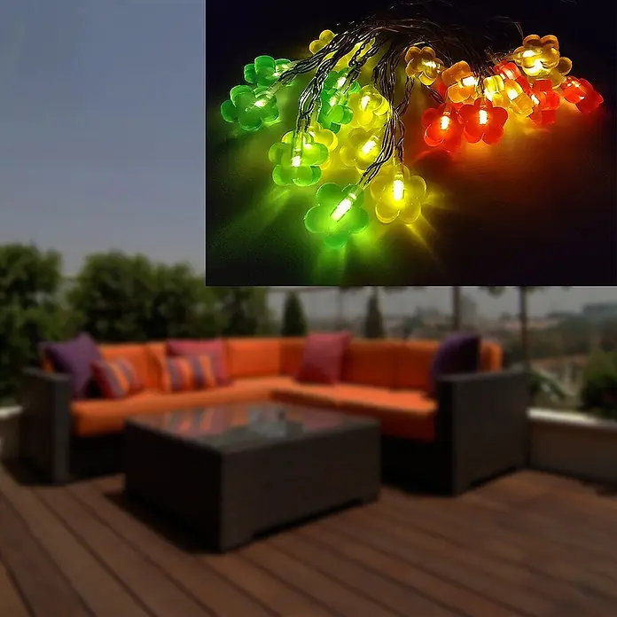 LED Solar-Lichterkette Blume 24flg. -  - Bunte blumenförmige LED-Lichterketten in Grün, Gelb, Orange und Rot beleuchten eine Terrasse.