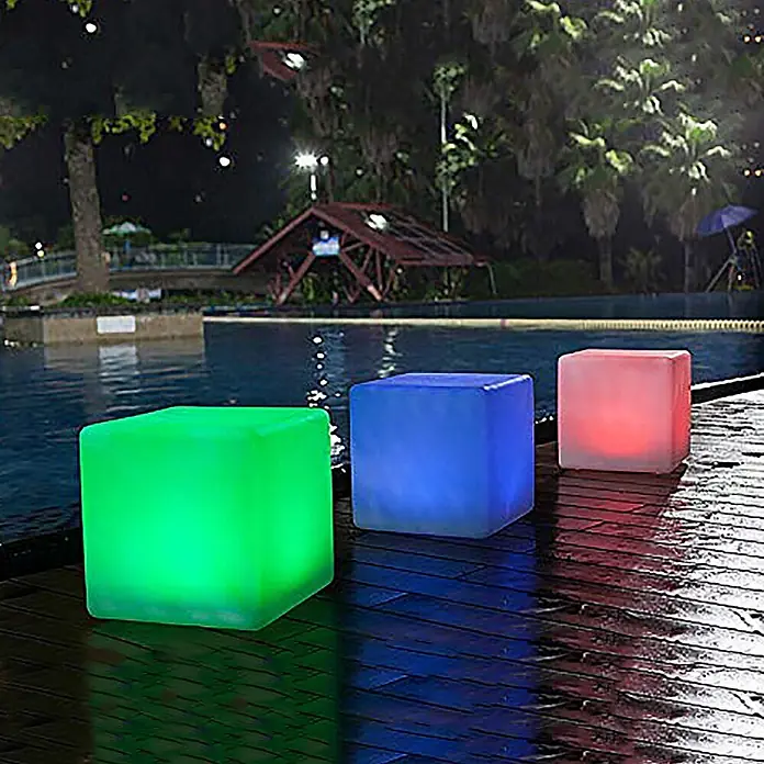 Solarleuchte Mate Würfel 40cm  farbwechselnd Gartendeko -  - Drei leuchtende Würfelhocker in Grün, Blau und Rot am Swimmingpool bei Nacht.