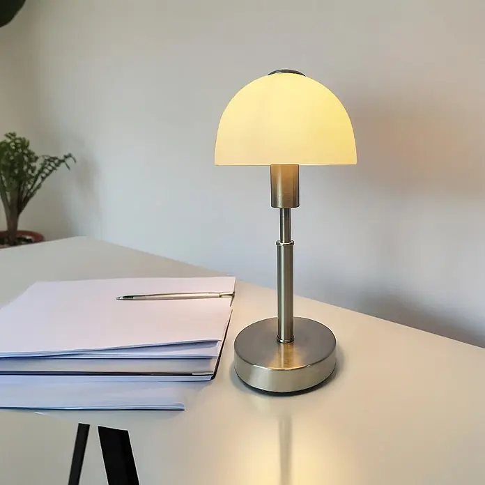 Nachttischlampe Maiolo Nickel Glasschirm -  - Gebürstete Metall-Tischlampe mit mattiertem Glas-Kuppelschirm, beleuchtet einen Schreibtisch mit Papieren und Stift.