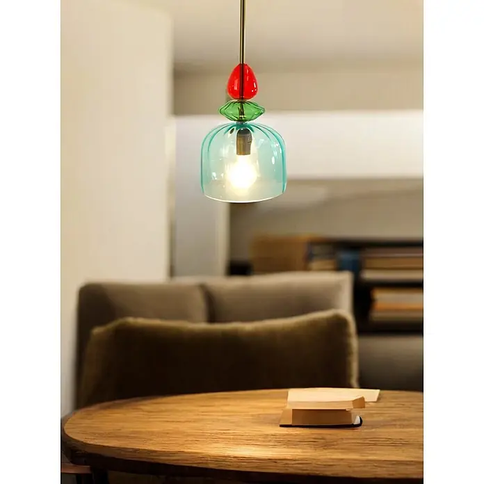 Pendelleuchte PIA einflammig Glasschirm -  - Bunte Hängeleuchte aus Glas beleuchtet einen Holztisch in einem modernen Wohnraum.