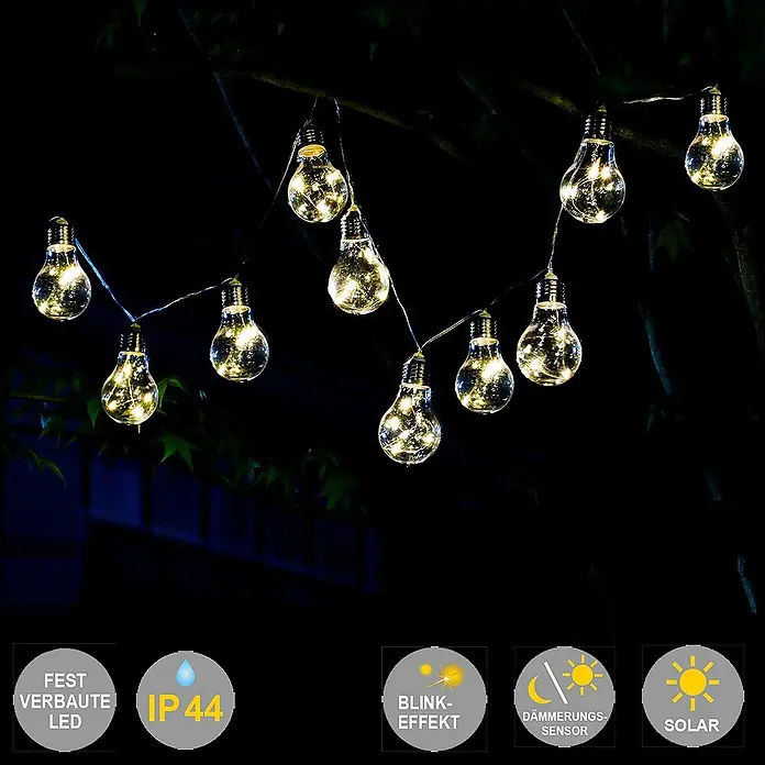 Solar-Lichterkette Glühbirne 10 flammig -  - Solarbetriebene LED-Lichterkette mit Glühbirnen im Vintage-Stil hängt nachts an Baumzweigen und strahlt warmes Licht aus.