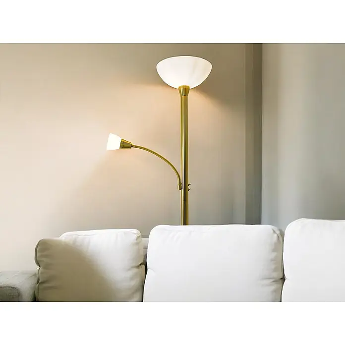 LED Stehleuchte Mattis messing mit Lesearm -  - Messingfarbene Stehlampe mit nach oben gerichtetem Schalenlicht und flexiblem Schwanenhals-Leselicht neben einem weißen Sofa.