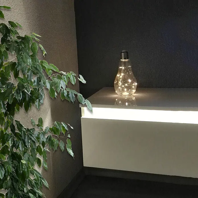 Dekoleuchte Tischlampe Glühbirne mit Lichterkette 20 LED batteriebetrieben -  - Dekorative Klarglas-Glühbirne mit warmweißen LED-Lichterketten darin, auf einem modernen Schrank in gedämpftem Licht.