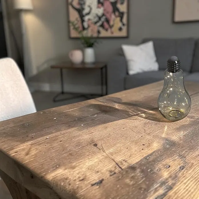 Dekoleuchte Tischlampe Glühbirne mit Lichterkette 20 LED batteriebetrieben -  - Glas-Glühbirnenlampe mit Lichterkette auf rustikalem Holztisch in Wohnzimmeratmosphäre.