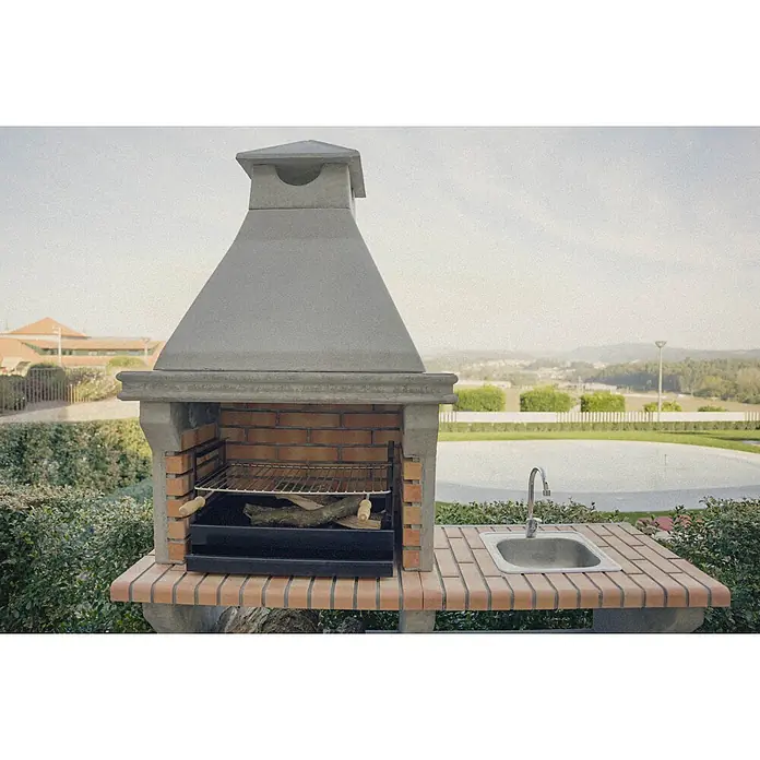 Sotnas Barbacoa de obra Ibiza - Gris/Ladrillo, An x Pr x Al: 168 x 60 x 219 cm, Superficie parrilla: 60 x 38 cm, Con fregadero - Barbacoa exterior de hormigón y ladrillo con parrilla metálica y fregadero de acero inoxidable integrado, en un jardín junto a una piscina.
