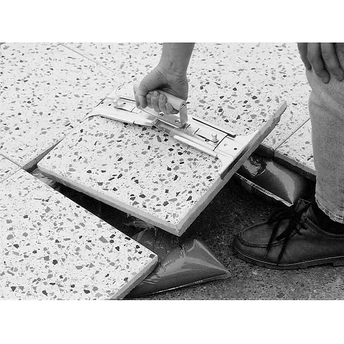 Heka Plattenheber - Verstellbar: 300 mm - 500 mm - Das Bild zeigt einen Fliesenheber beim Anheben einer Terrazzofliese, um sie zu verlegen oder zu reparieren. Das Werkzeug erleichtert die Arbeit.
