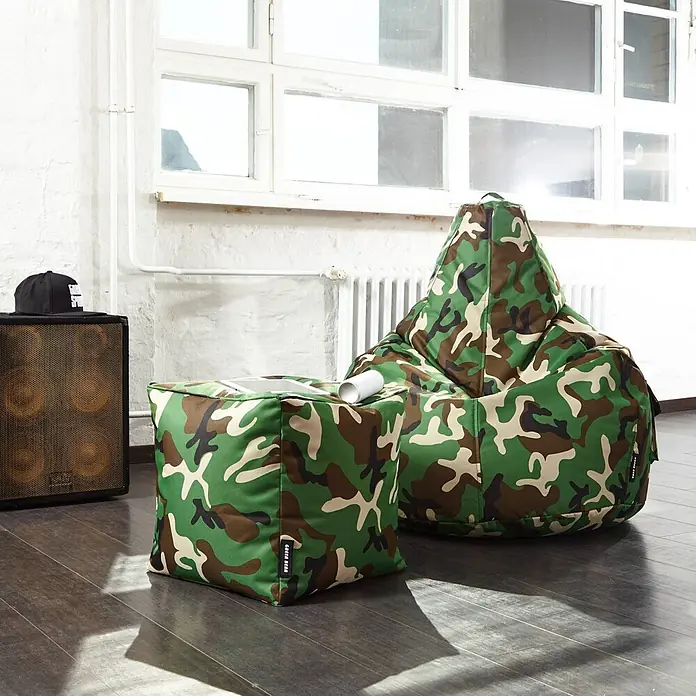 Green Bean Sitzhocker Cube mit EPS Füllung 40x40x40 cm Camouflage Grün -  - Ein tarnmusterbezogener Sitzsack und ein passender kubischer Hocker stehen auf dunklem Boden in einem Raum.