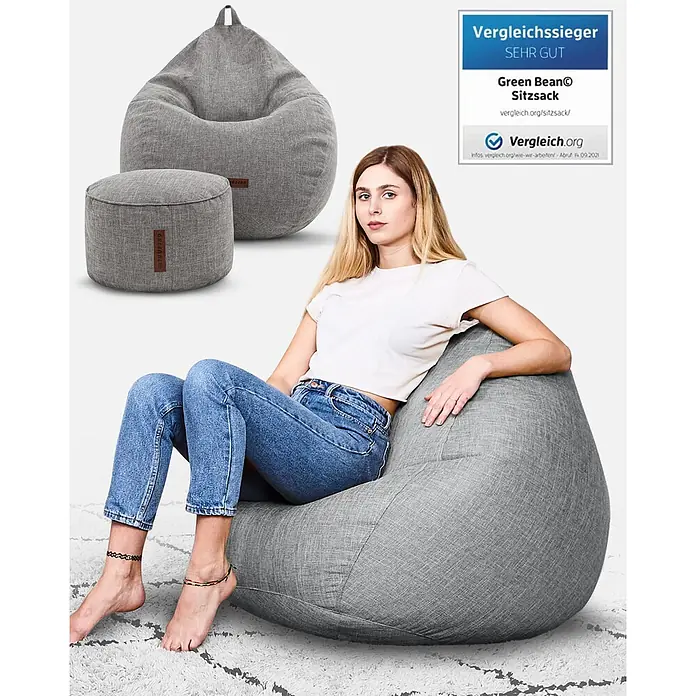 Green Bean Sitzsack Set Home Linen XXL mit Hocker 2 tlg. Silbergrau -  - Frau entspannt auf einem großen grauen Stoff-Sitzsack, daneben ein passender kleinerer Pouf. Beide sind aus strukturiertem grauen Stoff.