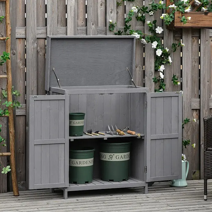 Furnicato Gartenschrank Tannenholz Grau L74 x B43 x H88 cm -  - Grauer Gartenlagerschrank aus Holz mit aufklappbarem Deckel und offenen Türen, der Gartentöpfe und Werkzeuge zeigt.