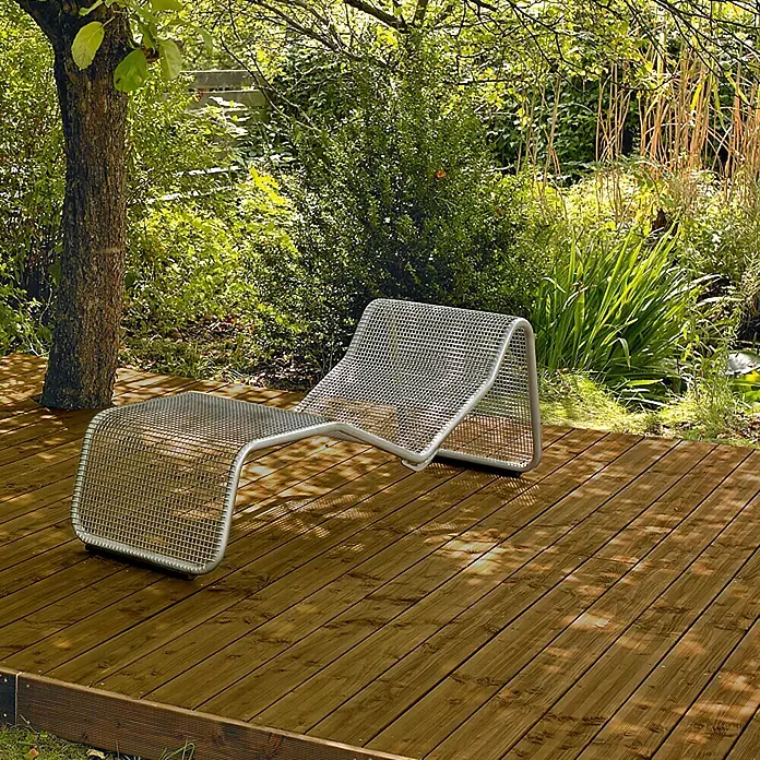 Tarima para terraza - Pino, 300 x 14,5 x 2,8 cm, Teca - Tumbona de jardín metálica sobre una terraza de madera rodeada de exuberante vegetación. Esta tumbona moderna es perfecta para relajarse al aire libre.