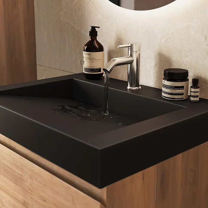 LOMAZOO Badmöbel Zarivo 60 cm Eiche hell, Waschbecken Schwarz -  - Modernes, matt-schwarzes Waschbecken mit Chromarmatur, aus der Wasser fließt, in einer Holzwaschtischplatte. Aesop-Produkte stehen darauf.