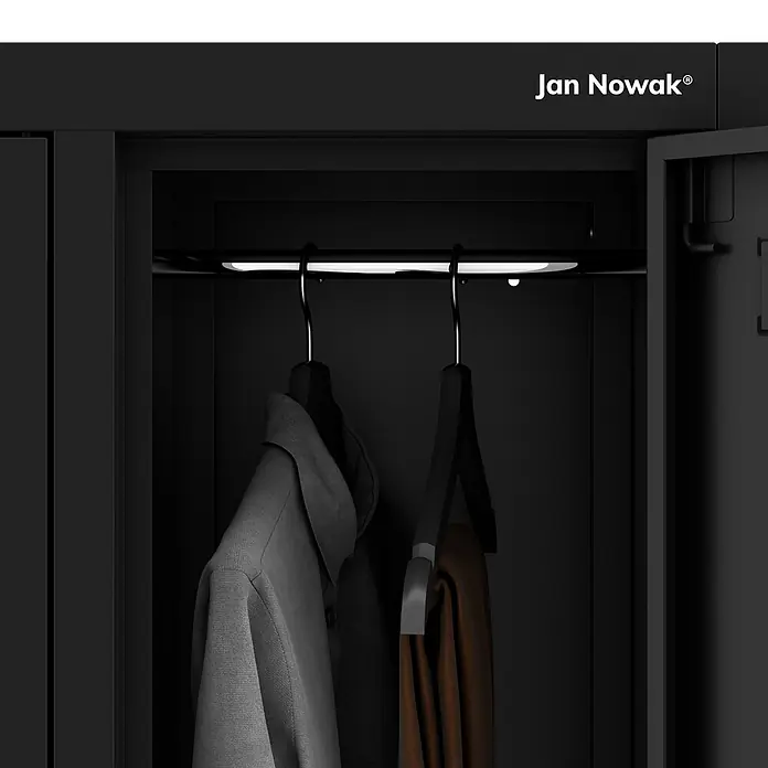 Jan Nowak Arbeitsschutzschrank BARTEK, 10-türig, 136x172x45 cm, Schwarz -  - Dunkler Metallschrank-Innenraum mit beleuchteter Stange, an der ein graues Hemd und braune Hosen hängen.