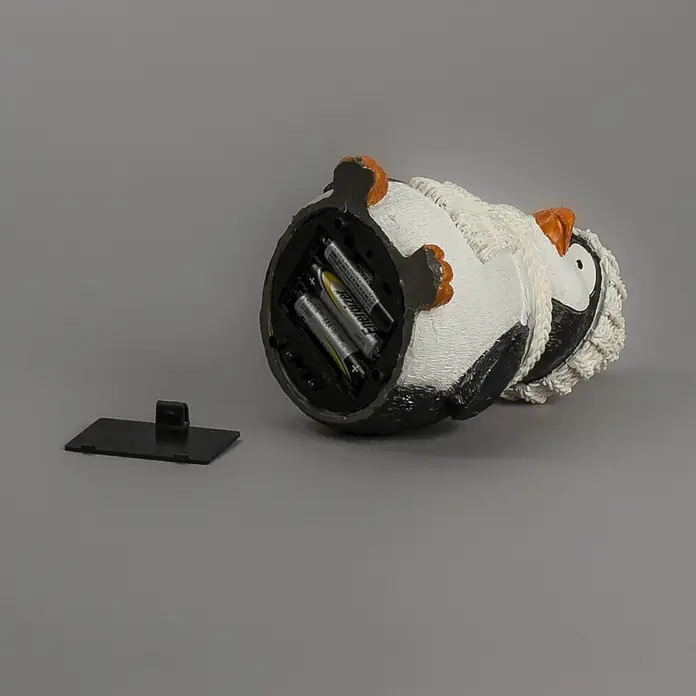 Konstsmide LED-Weihnachtsdekofigur - B x H: 9,5 x 15,5 cm, Lichtfarbe: RGB, Batteriebetrieben, LED - Pinguinfigur mit offenem Batteriefach, zwei AAA-Batterien innen und der schwarzen Abdeckung daneben.