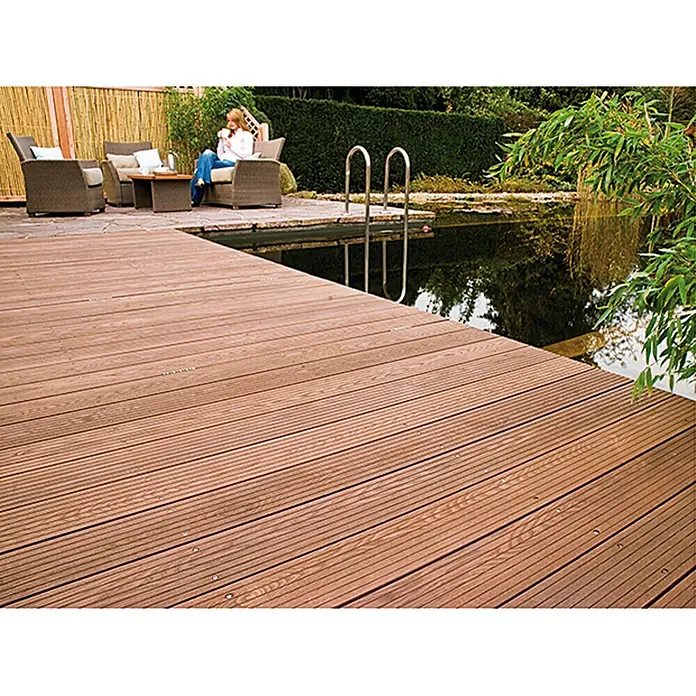 Osmo Bangkirai-Öl 006 - Naturgetönt, Transparent, 750 ml, Seidenmatt - Eine Terrassendiele aus braunem Holz führt zu einem Teich mit einer Leiter und einer Sitzgruppe mit einer Person im Hintergrund.
