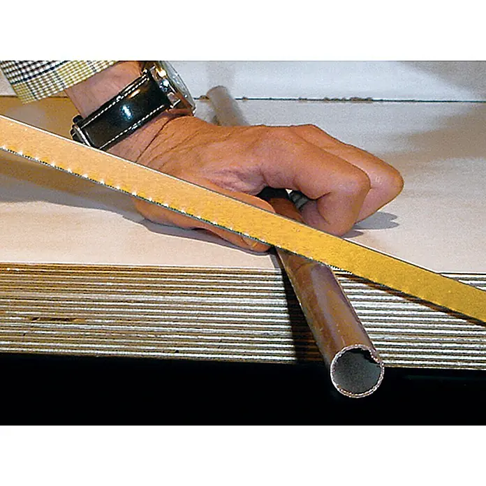Wisent Metallsäge - Stahl, Blattlänge: 300 mm - Nahaufnahme eines Mannes, der mit Schleifpapier ein Kupferrohr bearbeitet. Zu sehen sind Hand, Armbanduhr und ein Stück des karierten Hemds.
