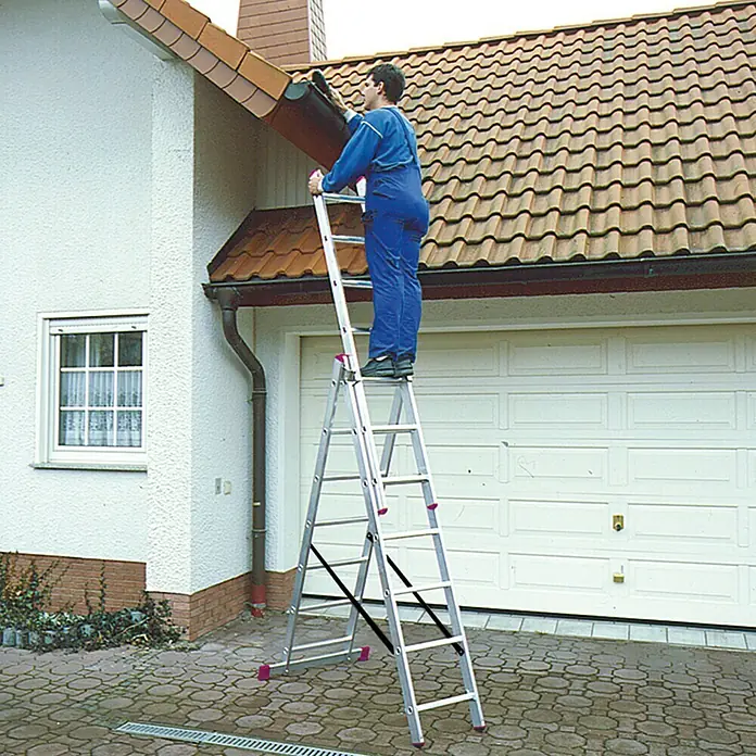 Krause Corda Mehrzweckleiter - Arbeitshöhe: 5,1 m, Anzahl Tritte: 21 Stk., Belastbarkeit: 150 kg, Aluminium - Mann auf einer Aluminium-Leiter, der die Dachrinne eines Hauses reinigt. Die Leiter steht auf Pflastersteinen.